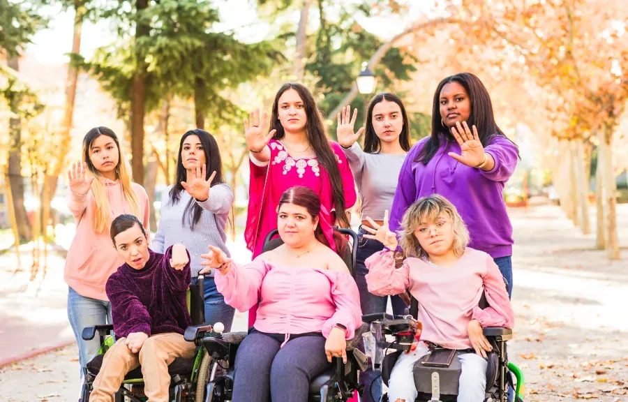 Group of young people, some using wheelchairs, waving together outdoors