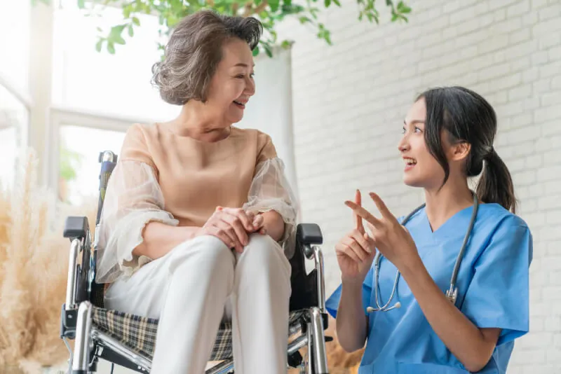 Nurse talking with an older woman seated in a wheelchair