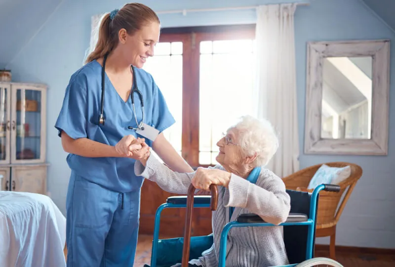 Nurse helping an older woman with a walking frame in her home