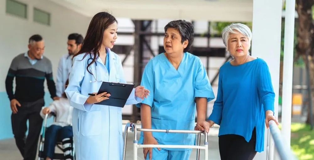Nurse with a clipboard walking beside a patient using a walking frame