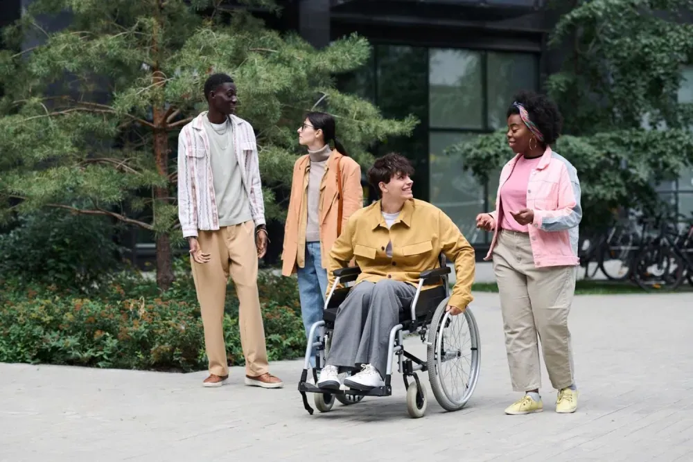 Woman in a wheelchair laughing with three friends on a footpath