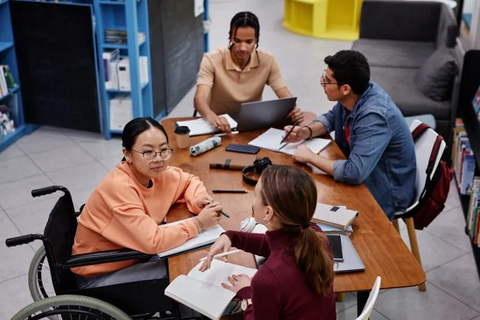 Four people including a woman in a wheelchair working together around a table