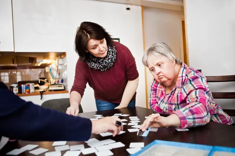 Support worker and a woman doing a puzzle together at a table