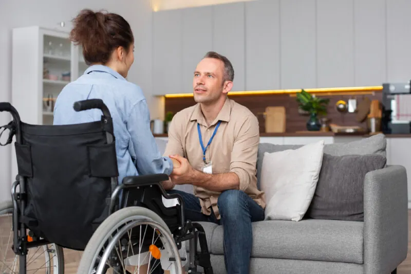 Support worker talking with a man in a wheelchair in a living room