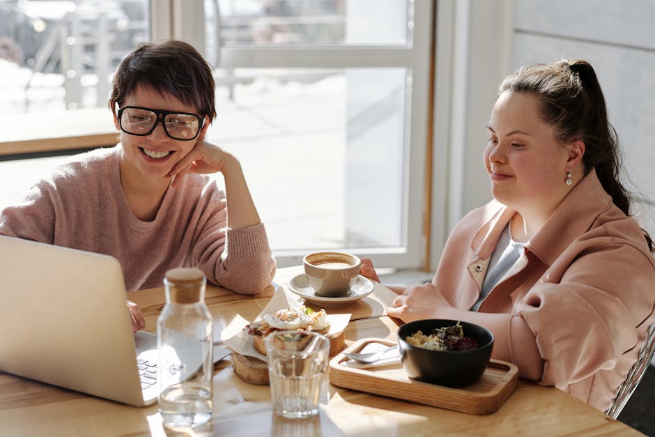 Two cheerful women enjoying coffee and food in a bright, modern indoor setting.